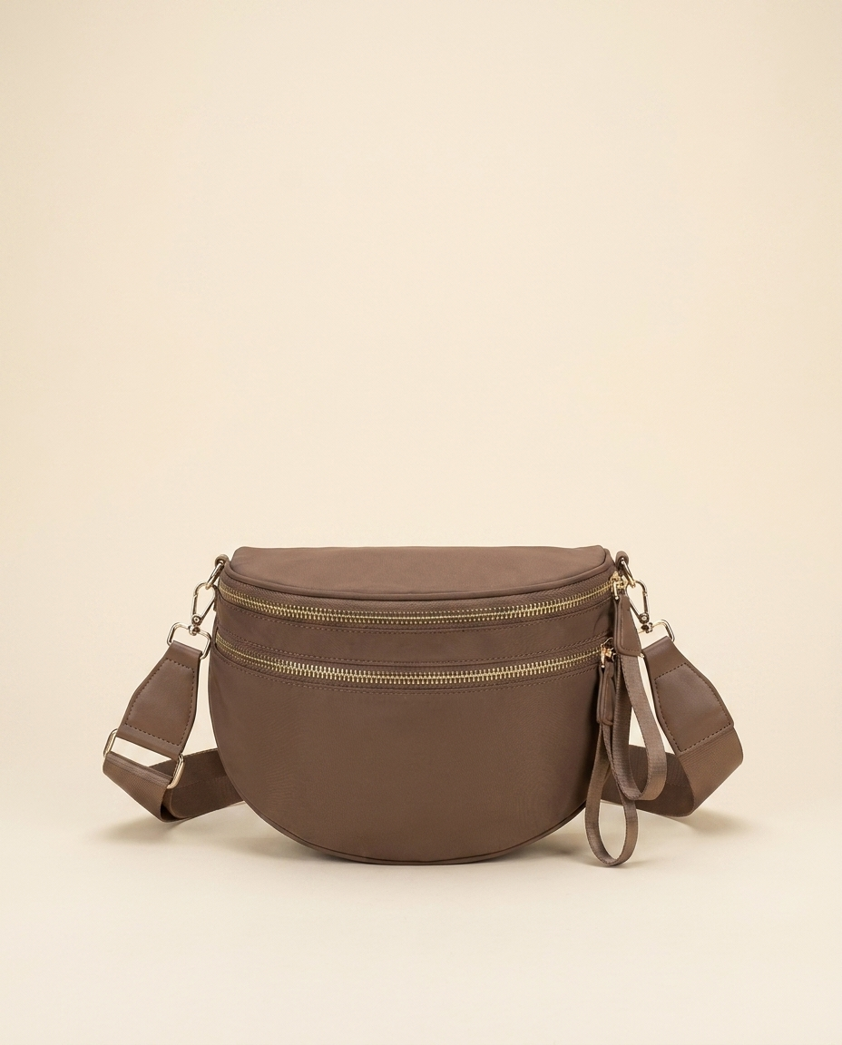 The Crescent Shoulder Bag in Taupe — front view, soft half-moon crossbody with double gold-tone zippers