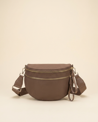 The Crescent Shoulder Bag in Taupe — front view, soft half-moon crossbody with double gold-tone zippers