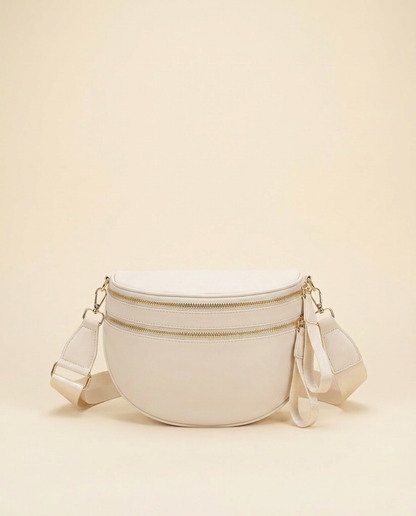 The Crescent Shoulder Bag in Sand — pale cream crossbody with gold-tone double zippers