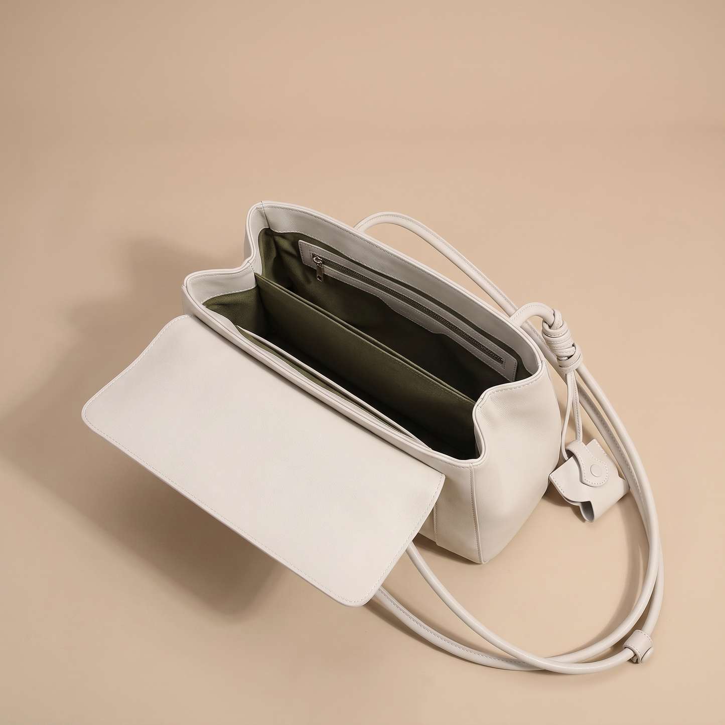 Colette bag opened to show the olive-lined interior with divider and zip pocket