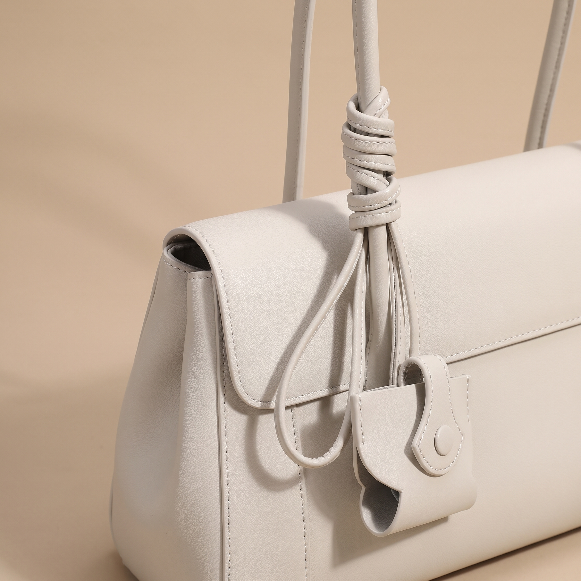 Close-up of the Colette bag's knotted double leather straps and hanging leather charm